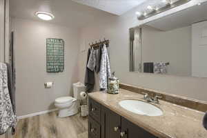 Bathroom featuring hardwood / wood-style floors, a textured ceiling, toilet, and vanity