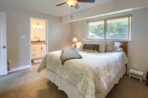 Bedroom featuring ceiling fan, carpet floors, and ensuite bath