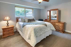 Bedroom with ceiling fan, light carpet, and multiple windows