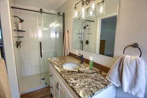 Bathroom featuring vanity, an enclosed shower, and wood-type flooring