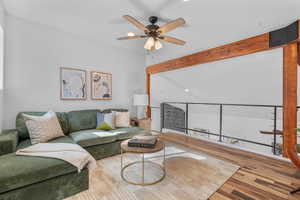 Living area with a ceiling fan, wood finished floors, and beamed ceiling