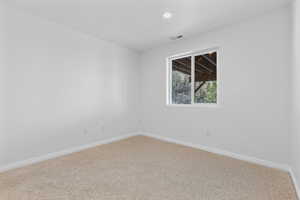 Empty room featuring carpet, visible vents, baseboards, and recessed lighting