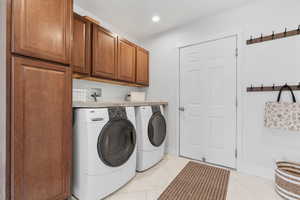 Clothes washing area with washing machine and dryer, recessed lighting, baseboards, marble finish floor, and cabinet space