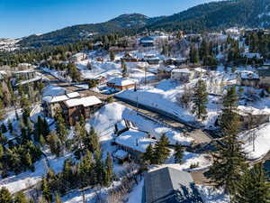 Snowy aerial view featuring a mountain view and a wooded view