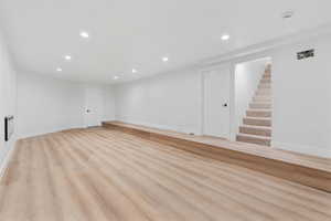 Basement with light wood-type flooring, baseboards, stairway, and recessed lighting