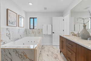 Bathroom with a jetted tub, marble finish floor, visible vents, and vanity