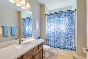 Bathroom with toilet, shower / tub combo, vanity, and tile patterned floors