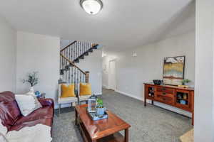 Carpeted living area featuring stairs and baseboards