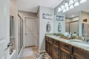 Bathroom featuring double vanity, a stall shower, tile patterned flooring, and a sink