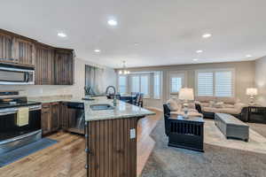 Kitchen featuring stainless steel appliances, light wood-style floors, a sink, light stone countertops