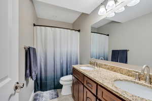 Bathroom with tile patterned floors, a sink, toilet, and double vanity