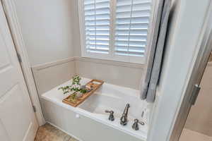 Bathroom featuring tile patterned flooring, a wainscoted wall, and a garden tub