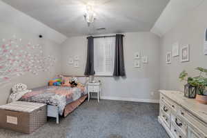 Carpeted bedroom with visible vents, vaulted ceiling, a notable chandelier, and baseboards