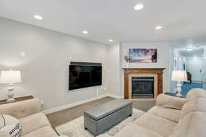 Living area featuring carpet floors, a fireplace, baseboards, and recessed lighting