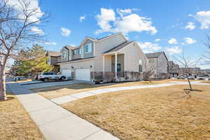 View of front facade with stucco siding, a front yard, a garage, a residential view, and driveway