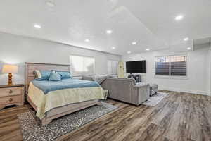 Bedroom with a textured ceiling, baseboards, wood finished floors, and recessed lighting