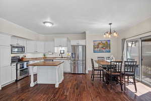 Kitchen featuring appliances with stainless steel finishes, butcher block counters, white cabinets, and a center island