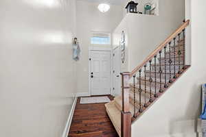 Entryway featuring stairs, a high ceiling, wood finished floors, and baseboards