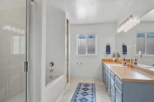 Bathroom with a textured ceiling, toilet, vanity, marble finish floor, and a shower with door