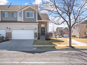 Townhome / multi-family property with board and batten siding, stone siding, a shingled roof, and concrete driveway