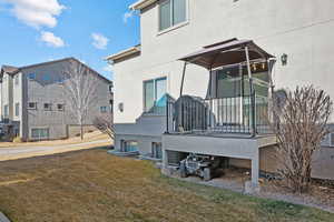 Rear view of house featuring a lawn and stucco siding