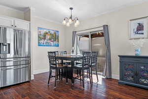 Dining room with dark wood-style floors, baseboards, and crown molding