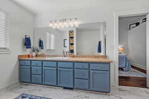 Full bath with marble finish floor, ensuite bath, vanity, and baseboards