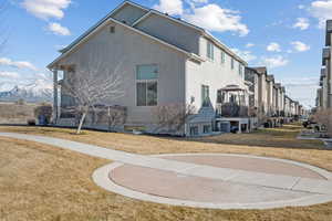 View of side of property with central AC unit, a lawn, a residential view, and stucco siding