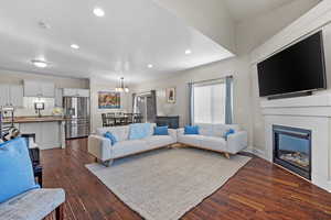 Living room with a chandelier, a fireplace, dark wood finished floors, and recessed lighting