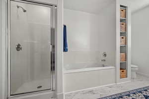 Bathroom featuring a garden tub, toilet, baseboards, marble finish floor, and a shower stall