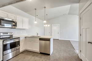 Kitchen with a sink, white cabinets, light countertops, appliances with stainless steel finishes, and light wood finished floors