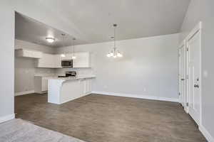 Kitchen with a breakfast bar area, appliances with stainless steel finishes, open floor plan, a chandelier, and a peninsula