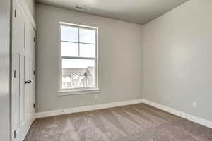 Carpeted empty room featuring visible vents and baseboards