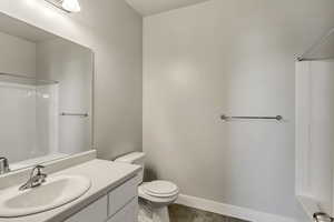 Bathroom featuring toilet, wood finished floors, vanity, baseboards, and a shower