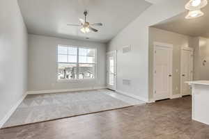 Interior space with lofted ceiling, visible vents, baseboards, and wood finished floors