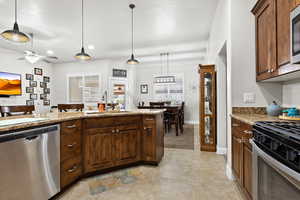 Kitchen featuring decorative light fixtures, appliances with stainless steel finishes, light tile patterned flooring, a sink, and ceiling fan