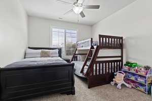 Carpeted bedroom with visible vents and a ceiling fan