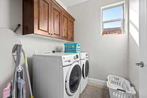 Washroom featuring cabinet space, baseboards, and washer and dryer