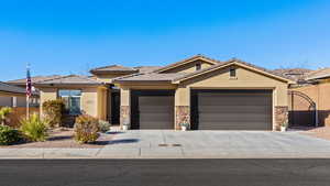 View of front facade featuring concrete driveway, stone siding, an attached garage, fence, and stucco siding