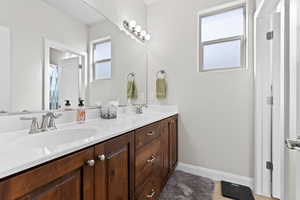 Full bathroom with double vanity, a sink, and baseboards