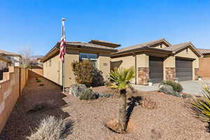 View of front of home with an attached garage, fence, stone siding, driveway, and stucco siding