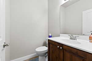 Bathroom featuring toilet, baseboards, and vanity