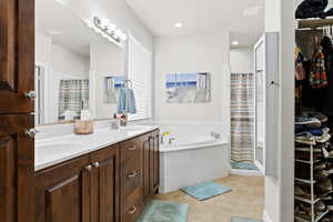 Full bathroom with tile patterned flooring, a sink, a bath, and double vanity