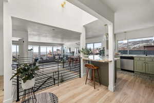 Kitchen featuring plenty of natural light, a sink, light wood finished floors, and stainless steel dishwasher