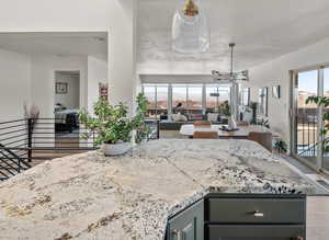 Kitchen with open floor plan, an inviting chandelier, gray cabinets, and light stone countertops