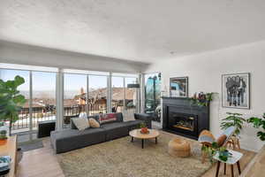 Living area featuring light wood-style floors, a fireplace with flush hearth, baseboards, and a textured ceiling