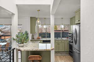 Kitchen with appliances with stainless steel finishes, green cabinetry, plenty of natural light, and light wood finished floors