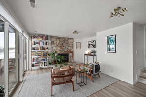 Living area featuring stairs, a fireplace, wood finished floors, and baseboards