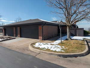 View of front facade featuring concrete driveway, brick siding, and a shingled roof