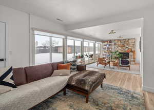 Living room featuring light wood finished floors, a fireplace, visible vents, and baseboards